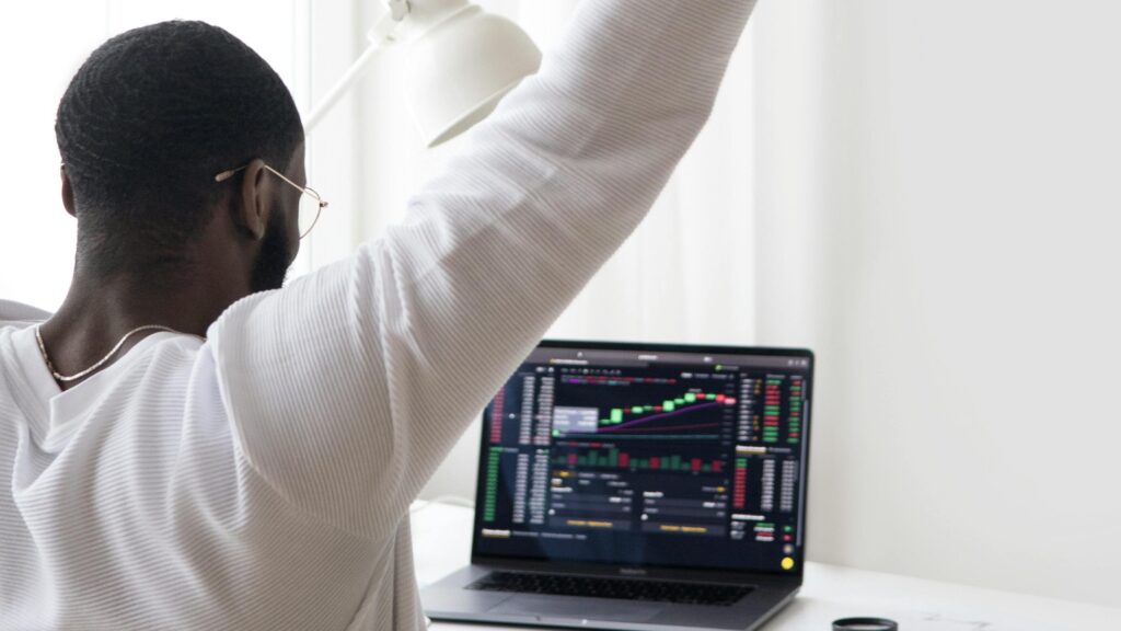 A man celebrates a successful stock market trade while sitting at his desk.