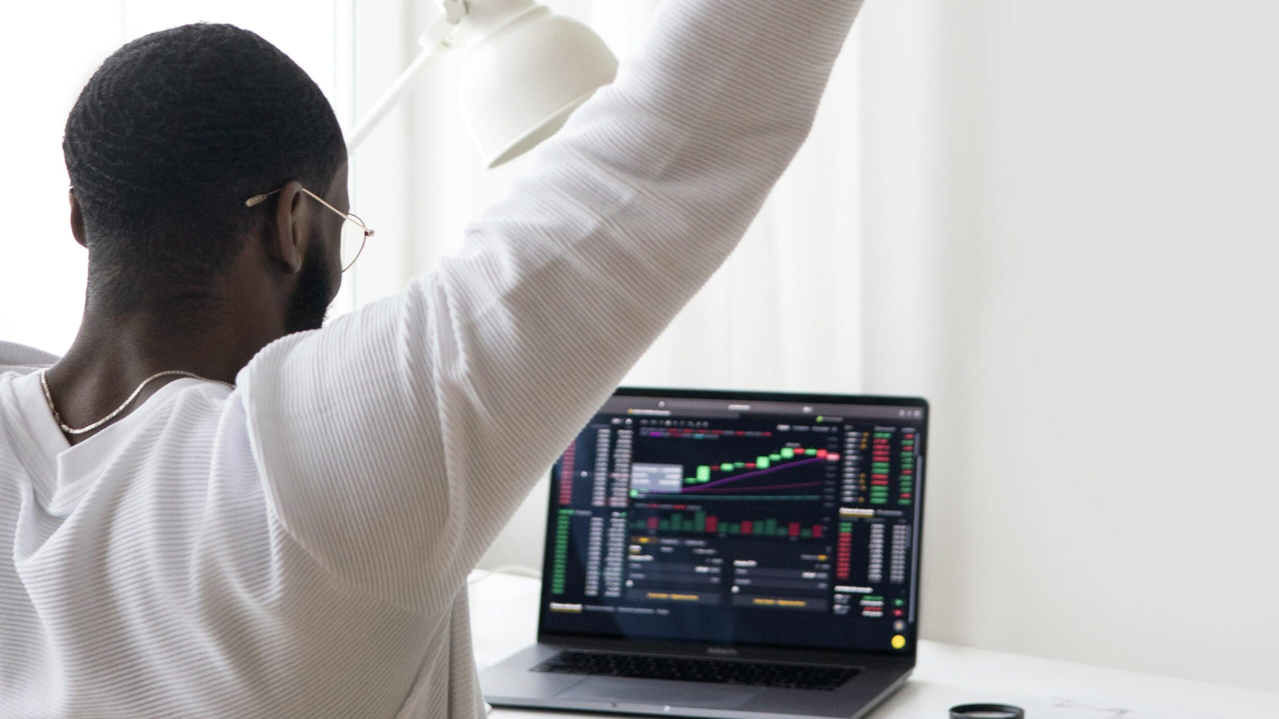 A man celebrates a successful stock market trade while sitting at his desk.
