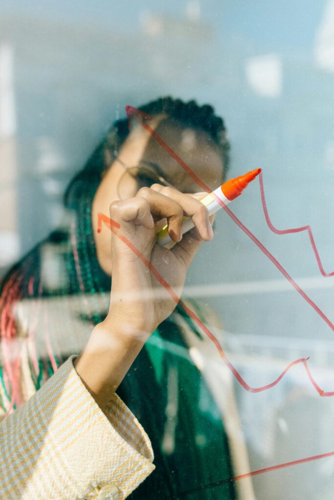 zipwp-image-7173047 A businesswoman draws a red financial graph on a glass panel, symbolizing strategy and success.